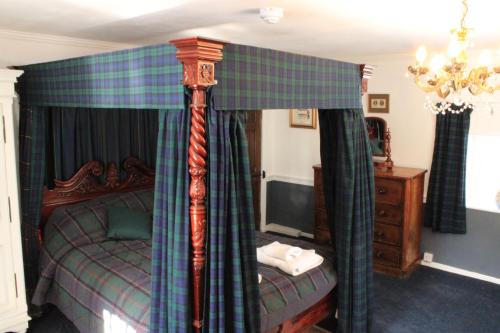 a bedroom with a canopy bed and a television at East Wing Lickleyhead Castle in Auchleven