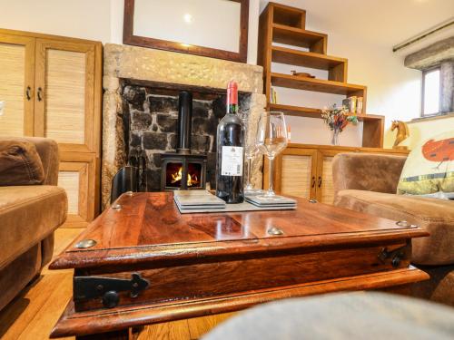 a bottle of wine on a table in a living room with a fireplace at Rake Hey Farm in Todmorden