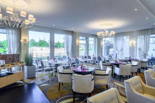 een restaurant met witte stoelen en tafels en ramen bij Crowne Plaza Maastricht in Maastricht