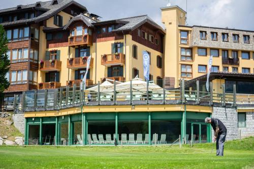 a man standing in the grass in front of a building at TH Madonna di Campiglio | Golf Hotel in Madonna di Campiglio