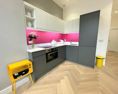 a kitchen with white cabinets and pink walls at Luxury Reno'd 1 Bed Nr Bruntsfield & The Meadows in Edinburgh