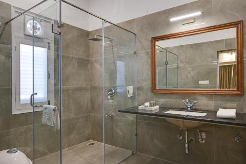 a bathroom with a shower and a sink and a mirror at Boheda Manor - Luxury Retreat in Udaipur