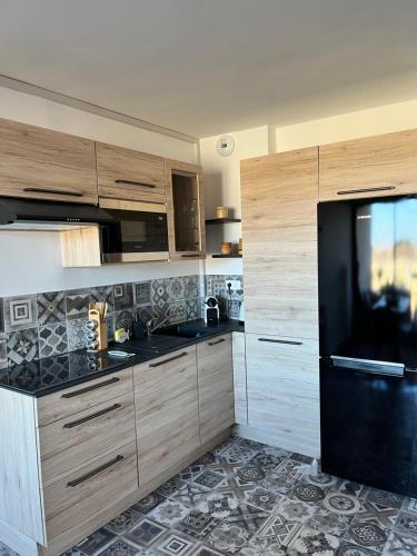 une cuisine avec des armoires en bois et un réfrigérateur noir dans l'établissement PORT GRIMAUD GOLFE ST TROPEZ BEL APPARTEMENT, à Grimaud