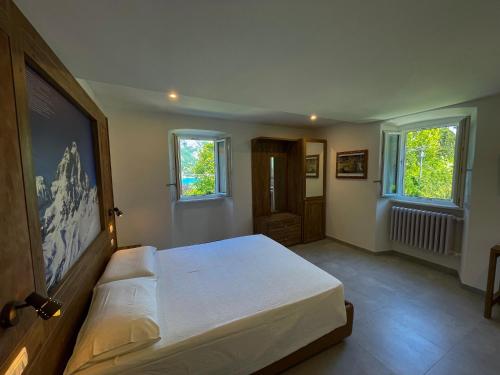 a bedroom with a large white bed with two windows at Bellagio Bed & Breakfast in Bellagio