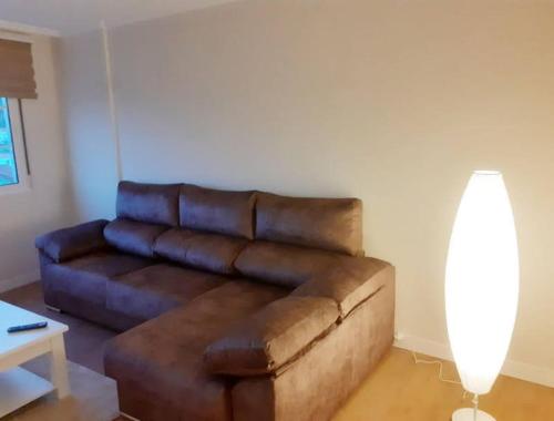 a brown leather couch in a living room with a lamp at APTO. SANXURXO in Camariñas