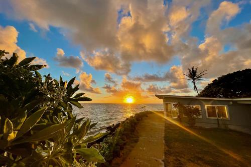 a house on the beach with the sunset in the background at Sea Turtle Cottage in Laie