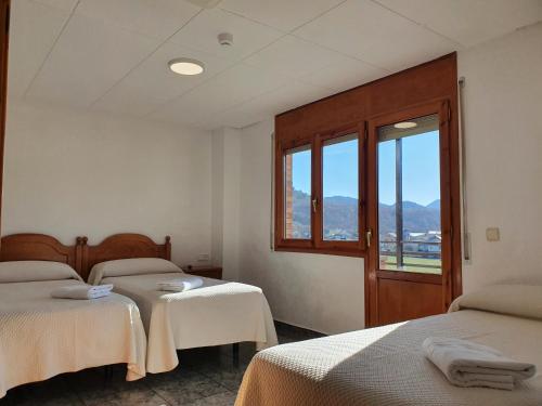 een kamer met 2 bedden en een raam bij Hostal Apolo XI in Aínsa