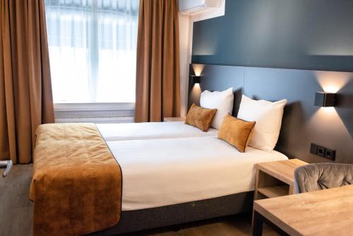 a hotel room with a bed and a window at Hotel et le Cafe de Paris in Apeldoorn