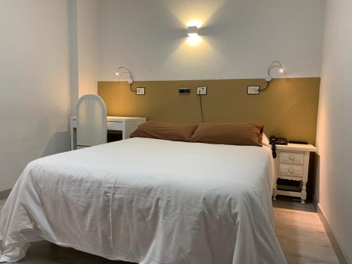 a bedroom with a large white bed and a desk at Hotel Los Olmos in Lugo