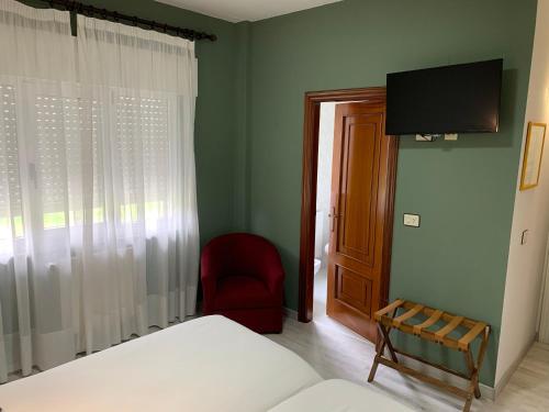 a bedroom with a bed and a chair and a television at Hotel Los Olmos in Lugo