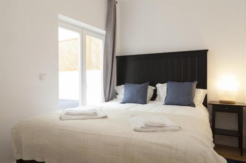 una camera da letto con un grande letto bianco con cuscini blu di Downtown Blue Terrace by Homing a Lisbona