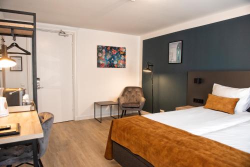 a hotel room with a bed and a chair at Hotel et le Cafe de Paris in Apeldoorn