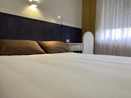 a bedroom with a large white bed and a window at Hotel Los Olmos in Lugo