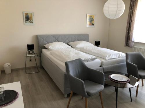 a bedroom with a bed with two chairs and a table at Pension Dabrunz in Heimbach