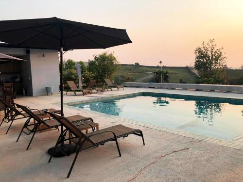 einen Pool mit Stühlen und einem Sonnenschirm in der Unterkunft Casa com piscina aquecida e churrasqueira em Itu in Aparecida