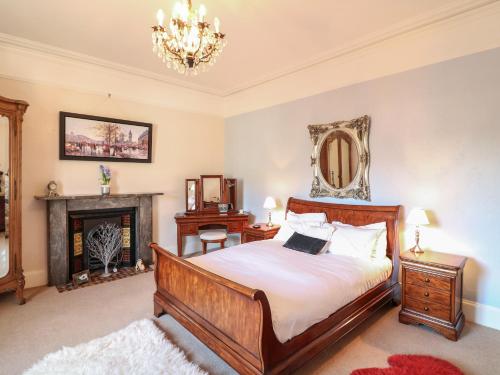 a bedroom with a bed and a fireplace and a chandelier at Clarence Grey House in Torquay