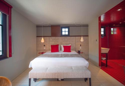 a bedroom with a bed with red pillows and a shower at Hotel Pont Levis - Franck Putelat in Carcassonne