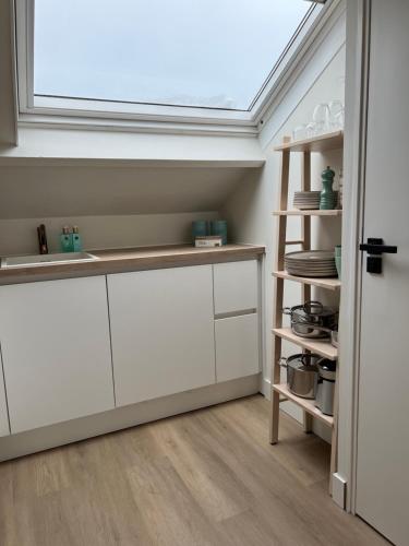 a kitchen with white cabinets and a skylight at Beach House Zandvoort in Zandvoort