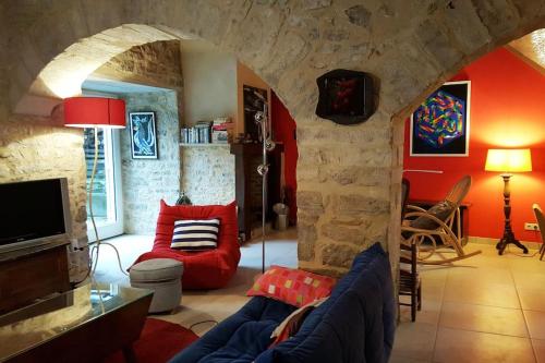 sala de estar con sofá azul y pared de piedra en Maison du XVème au cœur du village médiéval, en Martel