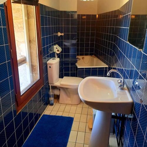 La salle de bains est pourvue de carrelage bleu, de toilettes et d'un lavabo. dans l'établissement Maison du XVème au cœur du village médiéval, à Martel