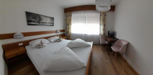 a bedroom with a white bed and a desk at Landhaus Weingut in Cornaiano
