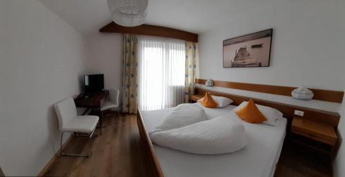 a bedroom with a bed with white sheets and orange pillows at Landhaus Weingut in Cornaiano