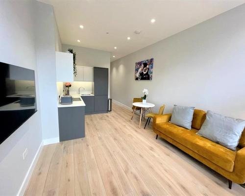 uma sala de estar com um sofá amarelo e uma cozinha em Chic, Newly Reno'd 1 Bed Open Plan, nr The Meadows em Edimburgo