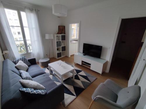 ein Wohnzimmer mit einem Sofa und einem TV in der Unterkunft Logement entier:Asnières sur Seine (10mn de Paris) in Asnières-sur-Seine