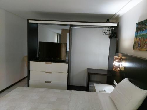 1 dormitorio con 1 cama, TV y espejo en Flat Particular 111 no Pipas Bay, en Pipa