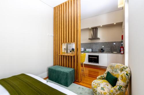 um quarto com uma cama e uma cadeira e uma cozinha em Mouzinho 129 - Medronheiro & Oliveira no Porto