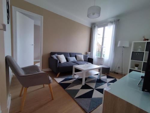 een woonkamer met een bank en een tafel bij Logement entier:Asnières sur Seine (10mn de Paris) in Asnières-sur-Seine