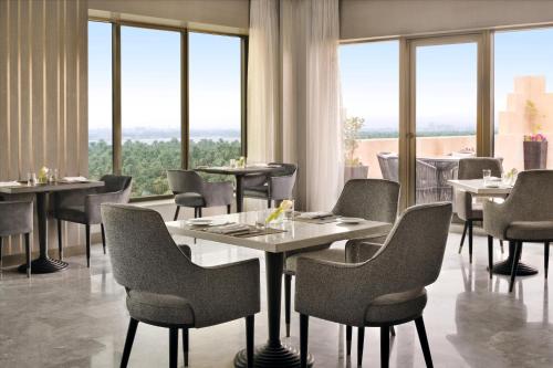 a restaurant with tables and chairs and large windows at Al Ahsa InterContinental by IHG in Al Ahsa