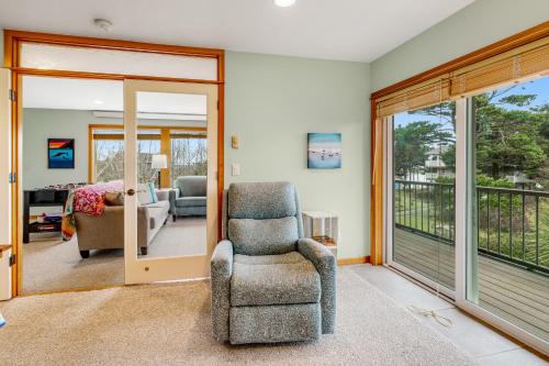 a living room with a chair and a balcony at Escape to the Cape in Tillamook