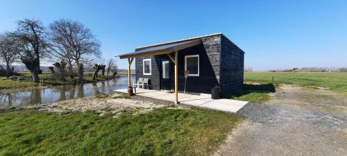 a small building in a field next to a river at La vache au lit in Damme