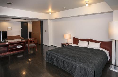 a bedroom with a bed and a desk and a television at The Residential Suites Fukuoka in Fukuoka