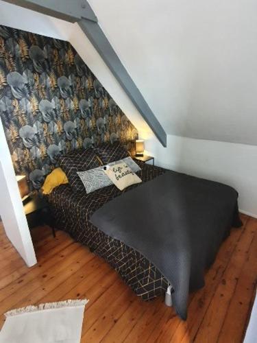 - une chambre avec un lit noir et un mur dans l'établissement studio centre ville 3ème étage sans ascenceur, à Saint-Pol-de-Léon