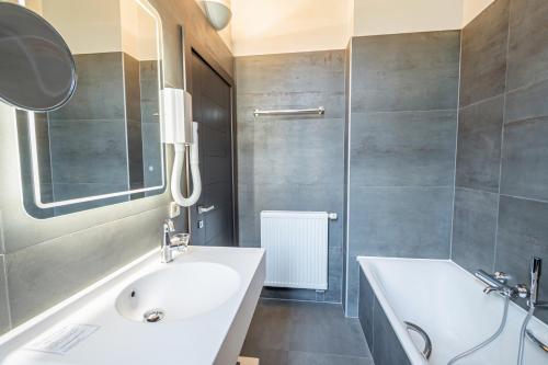 a bathroom with a white sink and a tub at Hotel des Comtes Durbuy in Durbuy