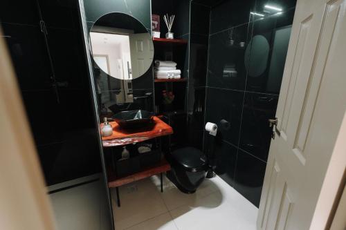 a black bathroom with a sink and a mirror at Bear's Apartment Alba Iulia in Alba Iulia