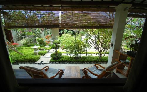 a room with a table and chairs and a garden at Frangipani Beach Hotel in Lovina