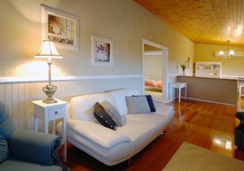 a living room with a white couch and a lamp at Barrington Hideaway- River Cottages in Gloucester