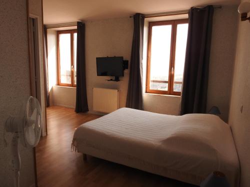 a bedroom with a bed and two windows and a television at Le Chalet in Antrenas