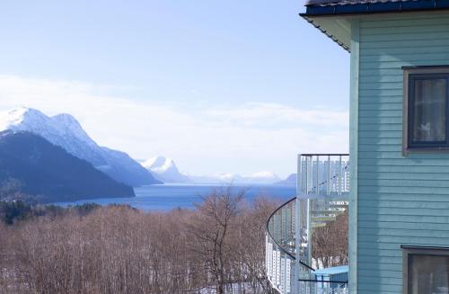 a house with a balcony overlooking a lake and mountains at Sjøholt Sommerhotell in Ørskog