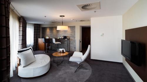 a living room with a couch and chairs and a television at Holiday Inn Łódź by IHG in Łódź