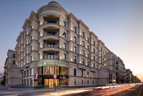 a large white building on a city street at Holiday Inn Łódź by IHG in Łódź