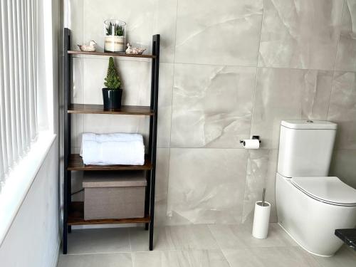 a bathroom with a toilet and a shelf with towels at High Grassings Country House in Ambleside