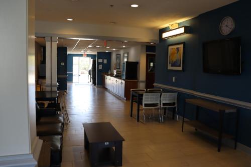 a living room with a table and a tv on the wall at Microtel Inn & Suites by Wyndham Columbus Near Fort Moore in Columbus