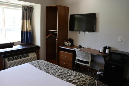 a hotel room with a desk and a television at Microtel Inn & Suites by Wyndham Columbus Near Fort Moore in Columbus