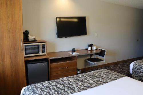 a hotel room with a bed and a desk with a microwave at Microtel Inn & Suites by Wyndham Columbus Near Fort Moore in Columbus