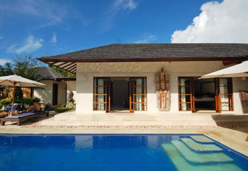 a villa with a swimming pool in front of a house at Frangipani Beach Hotel in Lovina