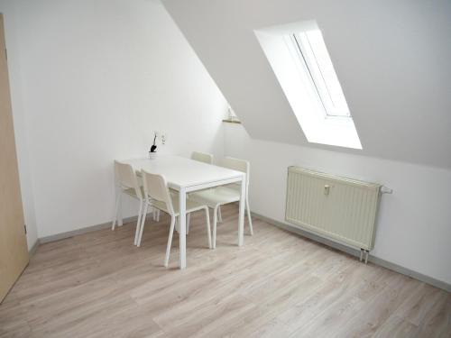 einen weißen Tisch und Stühle in einem Zimmer mit Fenster in der Unterkunft SUNNYHOME Monteurwohnungen und Apartments nahe Regensburg in Nittendorf